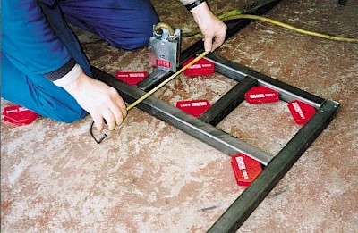 A worker using multiple smaller welding clamps at the same time
